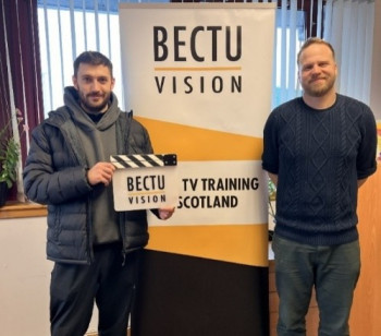 Two learners holding a clapperboard in front of a Bectu pop up stand